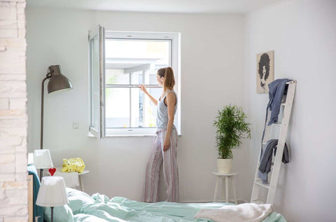 Woman using Insektenschutzrollo RO5/2 on window.