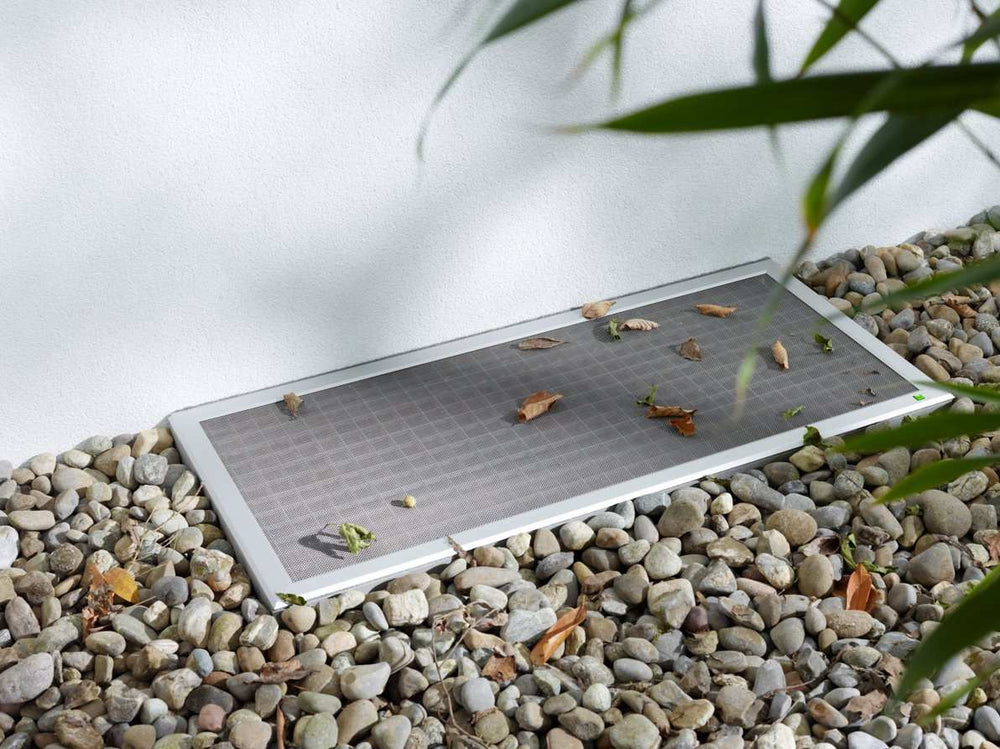 Lichtschachtabdeckung LI11 insect screen on gravel surface.